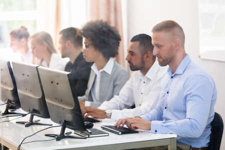 Young Business Executives Sitting In A Row Using Computerの写真素材