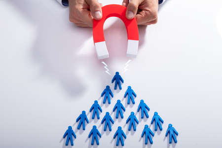 Businessman's Hand Attracting Blue Team With Horseshoe Magnet On White Backgroundの写真素材