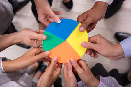 Elevated View Of Businesspeople Holding Multi Colored Pie Chartの写真素材