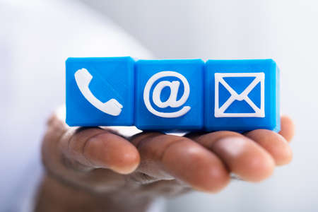 Macro Shot Of A Person's Hand Holding Three Blue Email Icon Blocks