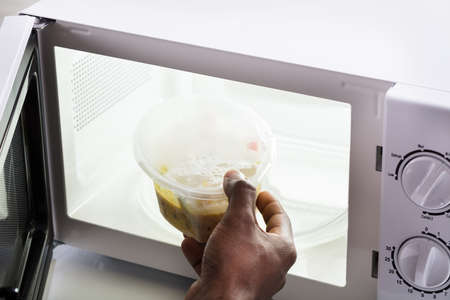 Close-up Of A Man's Hand Heating Food In Microwave Ovenの写真素材