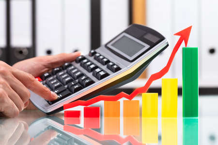 Colorful Graph With Arrow Going Upwards Near Businessperson Using Calculatorの写真素材