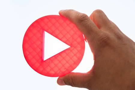 Close-up of a person's hand holding red play iconの写真素材