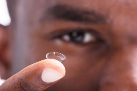 Close-up Of A Man Holding Transparent Contact Lens In His Fingerの写真素材