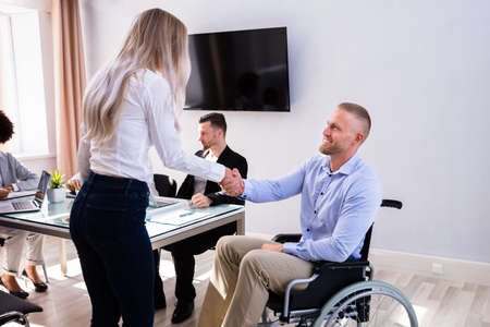Disabled Happy Businessman Shaking Hand With His Female Colleague In Officeの写真素材