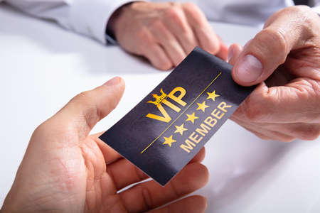 Businessperson Giving VIP Card To His Partner Over White Desk