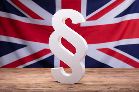 White Paragraph Symbol On Wooden Desk In Front Of England Flagの写真素材