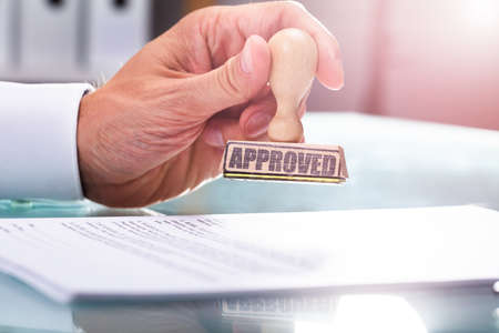 Close-up Of A Businessman's Hand Stamping Approved On Documentの写真素材