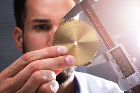 Close-up Of A Man's Hand Measuring Gear's Size With Digital Electronic Vernier Caliperの写真素材