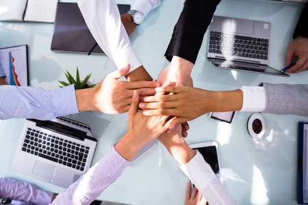 Group Of Businesspeople Stacking Hands Over Desk In Officeの写真素材