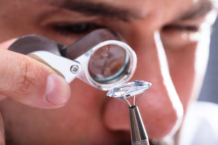 Close-up Of A Male Jeweler's Hand Looking At Diamond Through Magnifying Loupe