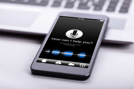 Smart Phone On Desk With Screen Showing How Can I Help You? Text