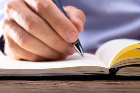 Person's Hand Writing In Notebook Using Pen