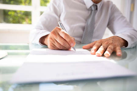 Businessman's Hand Filling Contract Form With Pen