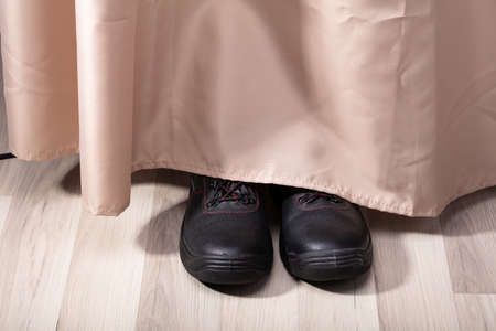 View Of A Person Shoe's Hiding Behind Curtain