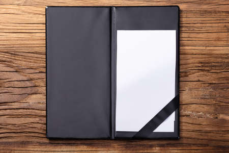 Overhead View Of Blank Empty White Paper In Black Leather Folder On Wooden Tableの写真素材
