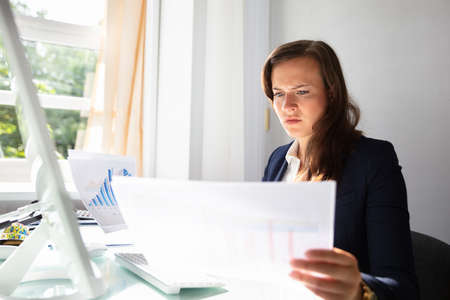 Concentrated Young Businesswoman Looking At Documents In Office