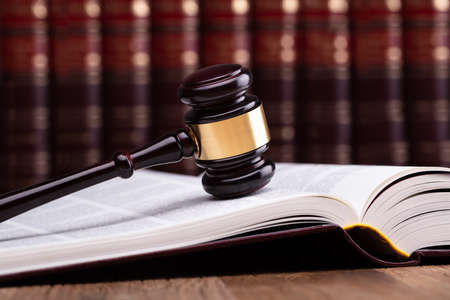 Close-up Of Wooden Gavel On Open Law Book