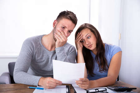 Portrait Of A Sad Young Couple Looking At Invoice