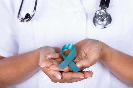 Close-up Of A Female Doctor's Hand With Teal Ribbon Showing Ovarian Cancer Awareness
