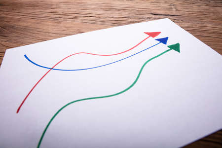 Close-up Of Colorful Arrows Drawn On Paper Over Wooden Desk