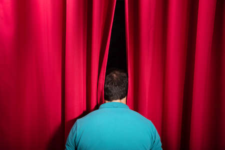 Rear View Of A Man Peeking Through A Red Stage Curtainの写真素材