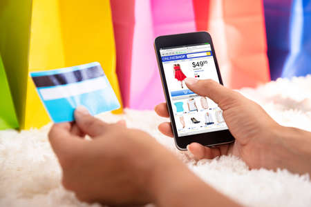 Woman's Hand Using Credit Card For Shopping Online On Smartphone