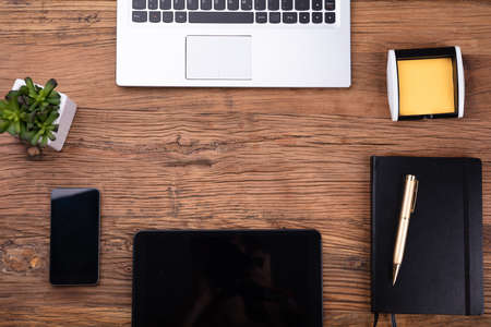 Overhead View Of Office Supplies And Electronic Gadgets On Wooden Deskの写真素材