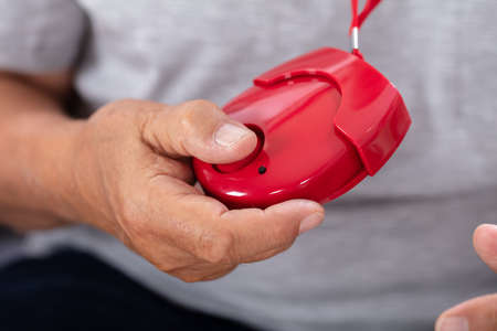 Close-up Of A Senior Man's Hand Holding Red Personal Alarm