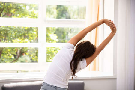 Woman Stretching Her Arms In Front Of Window