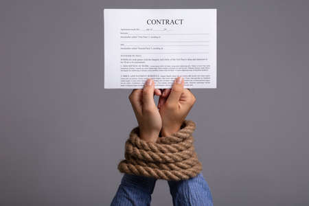 Woman's Hand Tied With Rope Holding Contract Form On Grey Backgroundの写真素材