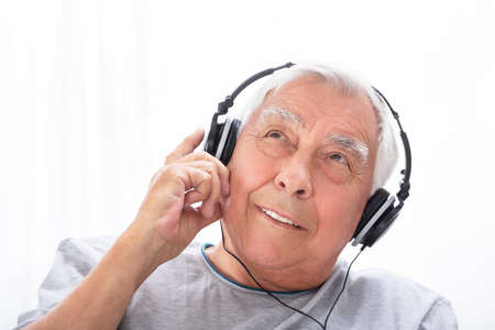 Portrait Of A Senior Man Listening To Music On Headphone At Home