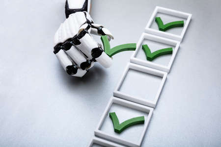 Robotic Hand Placing Check Mark In Box On Grey Backgroundの写真素材