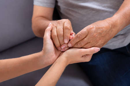 Close-up Of A Daughter Holding Her Elderly Father's Hand