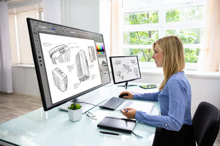 Side View Of A Young Female Designer Using Graphic Tablet While Working On Computer