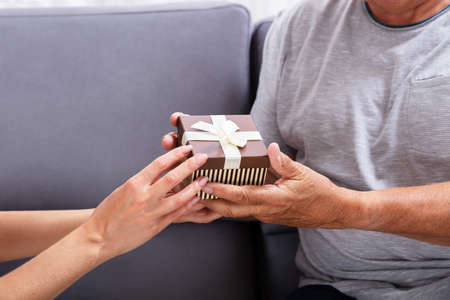 Close-up Of A Father And Daughter's Hand Holding Gift