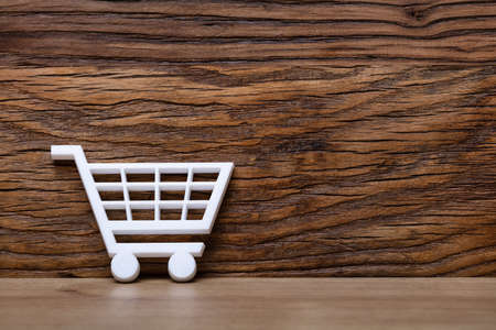 White Shopping Cart Leaning On Wooden Wallの写真素材