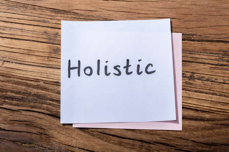 Elevated View Of Holistic Word On Adhesive Note Over Wooden Backgroundの写真素材