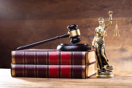 Close-up Of Golden Lady Justice Near Wooden Gavel Over Law Bookの写真素材