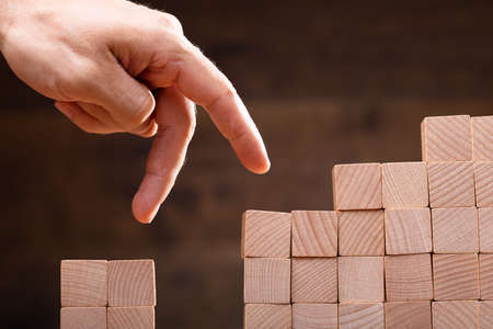 Close-up Of A Person Stepping Finger On Stacked Wooden Blocksの写真素材