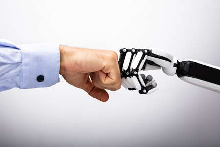 Human Hand And Robot Making Fist Bump On Gray Backgroundの写真素材