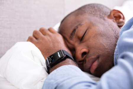 Close-up Of A Man Sleeping With Smart Watch In His Hand Showing Heartbeat Rateの写真素材
