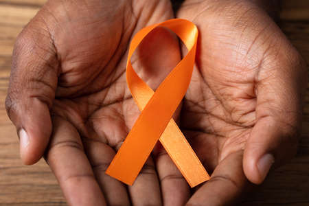 Person's Hand Holding Ribbon To Support Kidney Cancer And Leukemia Awareness
