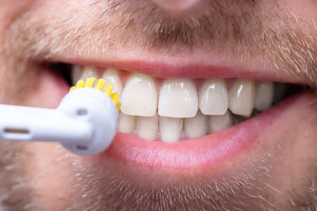 Close-up Of A Man Brushing Teeth With Electric Brushの写真素材
