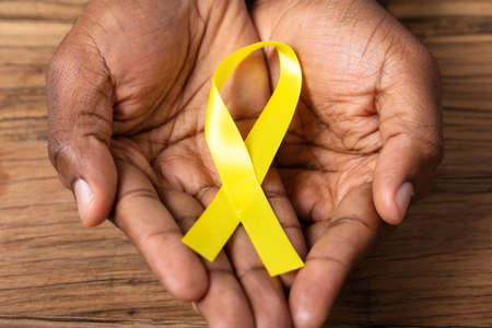 Person's Hand Holding Ribbon To Support Childhood And Bladder Cancer