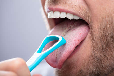 Close-up Of A Man Cleaning His Tongue With Cleanerの写真素材