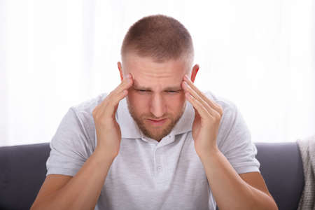 Portrait Of A Young Man Suffering From Headache At Home