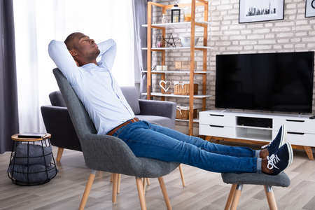 Side View Of A Young Man Relaxing On Chair At Homeの写真素材