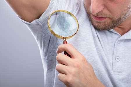 Close-up Of A Man Looking At Sweaty Armpit Through Magnifying Glass
