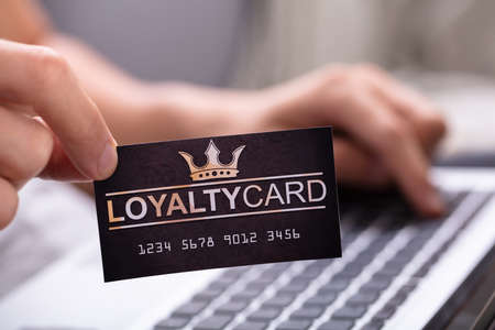 Close-up Of A Man's Hand Holding Loyalty Card While Using Laptopの写真素材